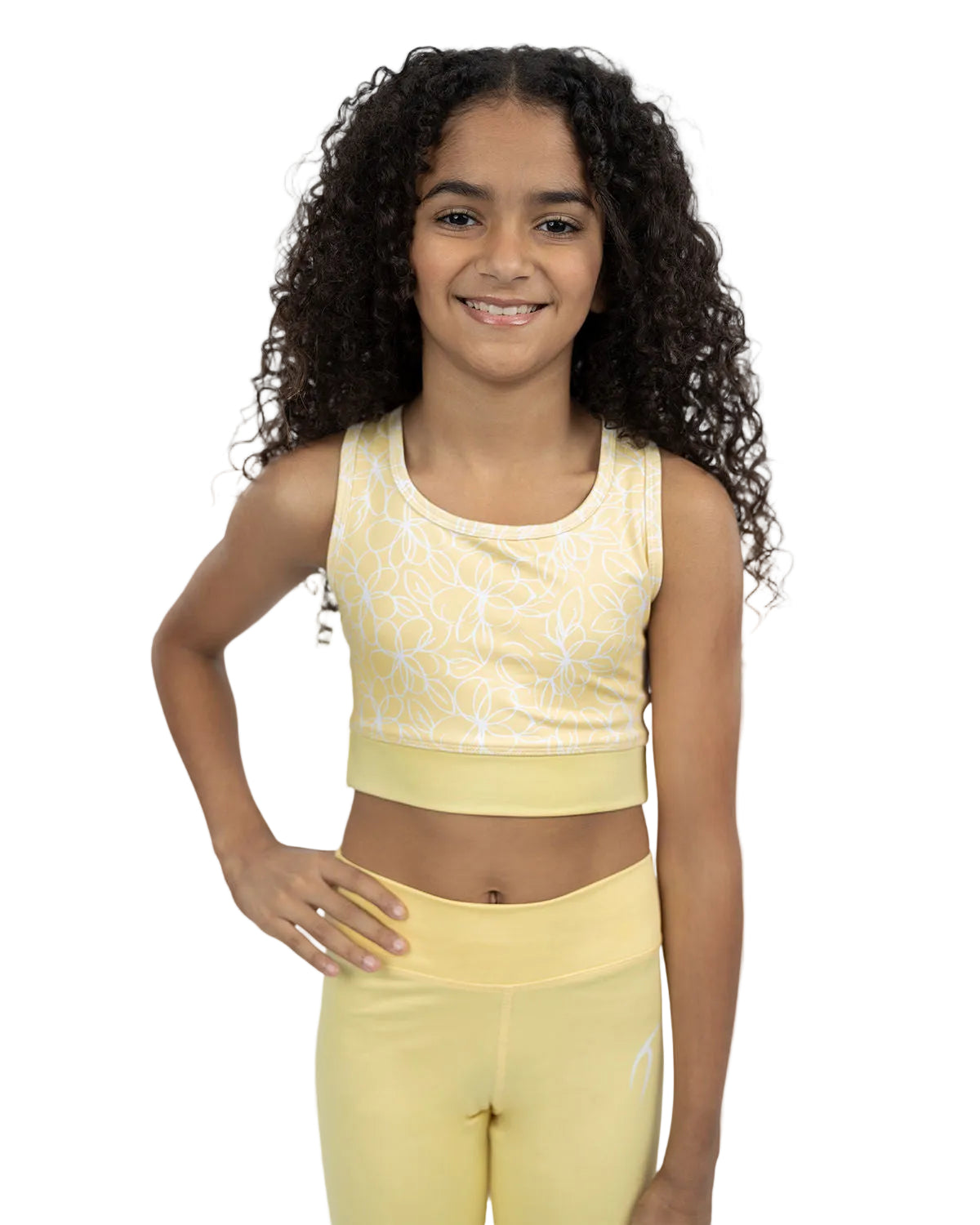 Young girl wearing a yellow athletic outfit on a plain background